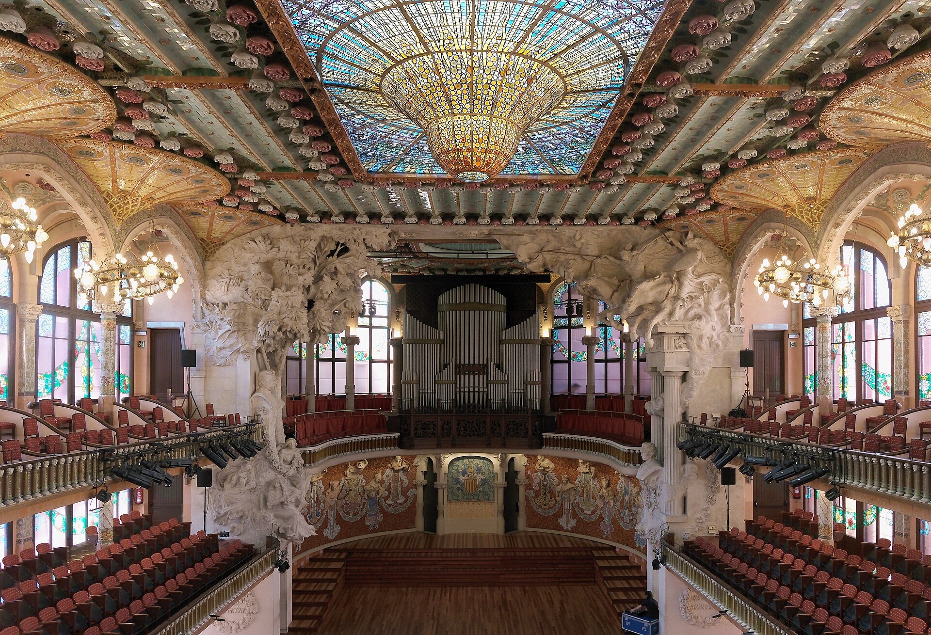 la sala del palau de la musica catalana vista dalla platea, con l’organo, le pareti di vetrate e il lucernario dorato sul soffitto