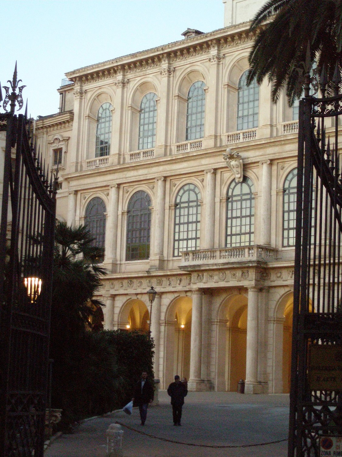 la facciata di Palazzo Barberini a Roma vista dal cancello, con lo stemma delle api barberiniane e il portico illuminato