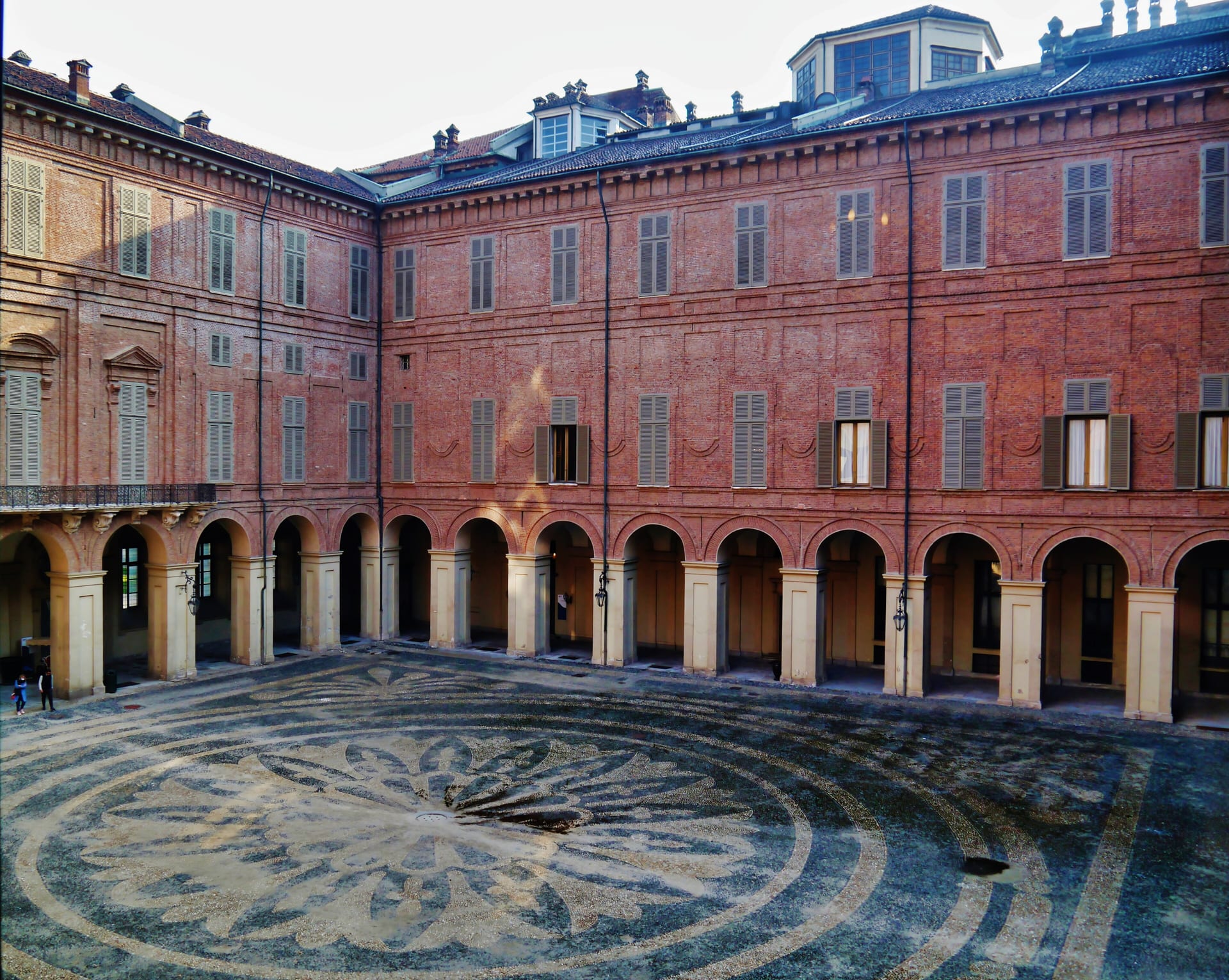 the courtyard of the royal palace in turin with its columned arcade and the cobblestone pattern in the paving