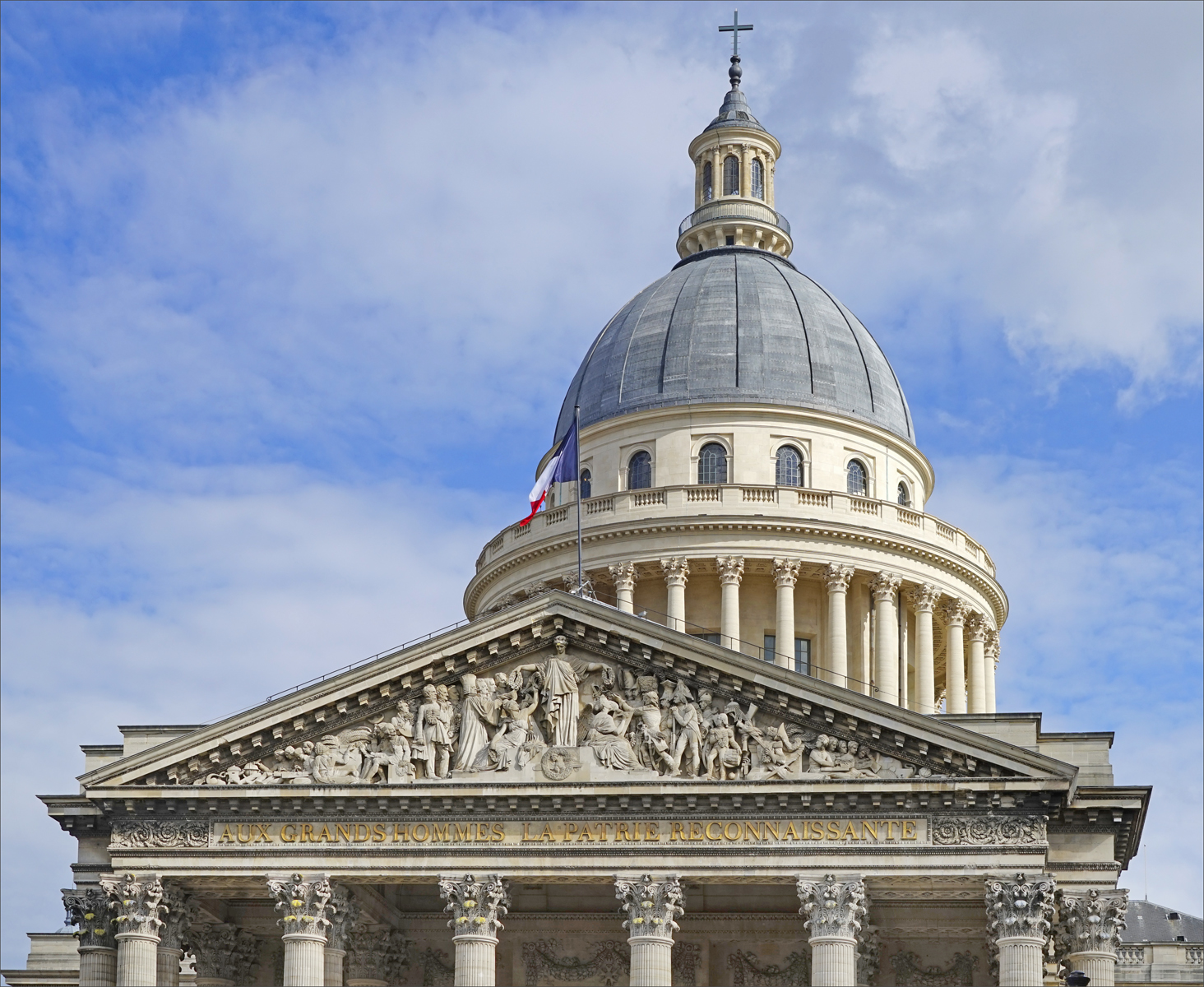 il timpano scolpito del pantheon con la scritta dorata aux grands hommes la patrie reconnaissante sull architrave, la bandiera francese sul tamburo, il colonnato circolare e la cupola grigia sormontata dalla lanterna con una croce