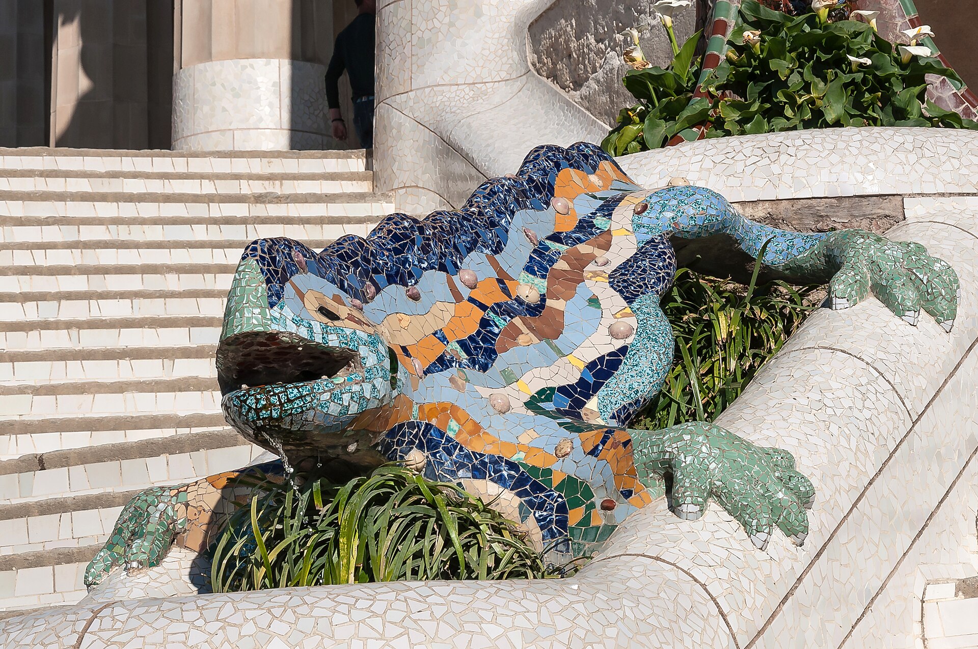 il drago della scalinata di park guell, coperto di cocci di ceramica blu, gialli e arancioni, con la bocca aperta