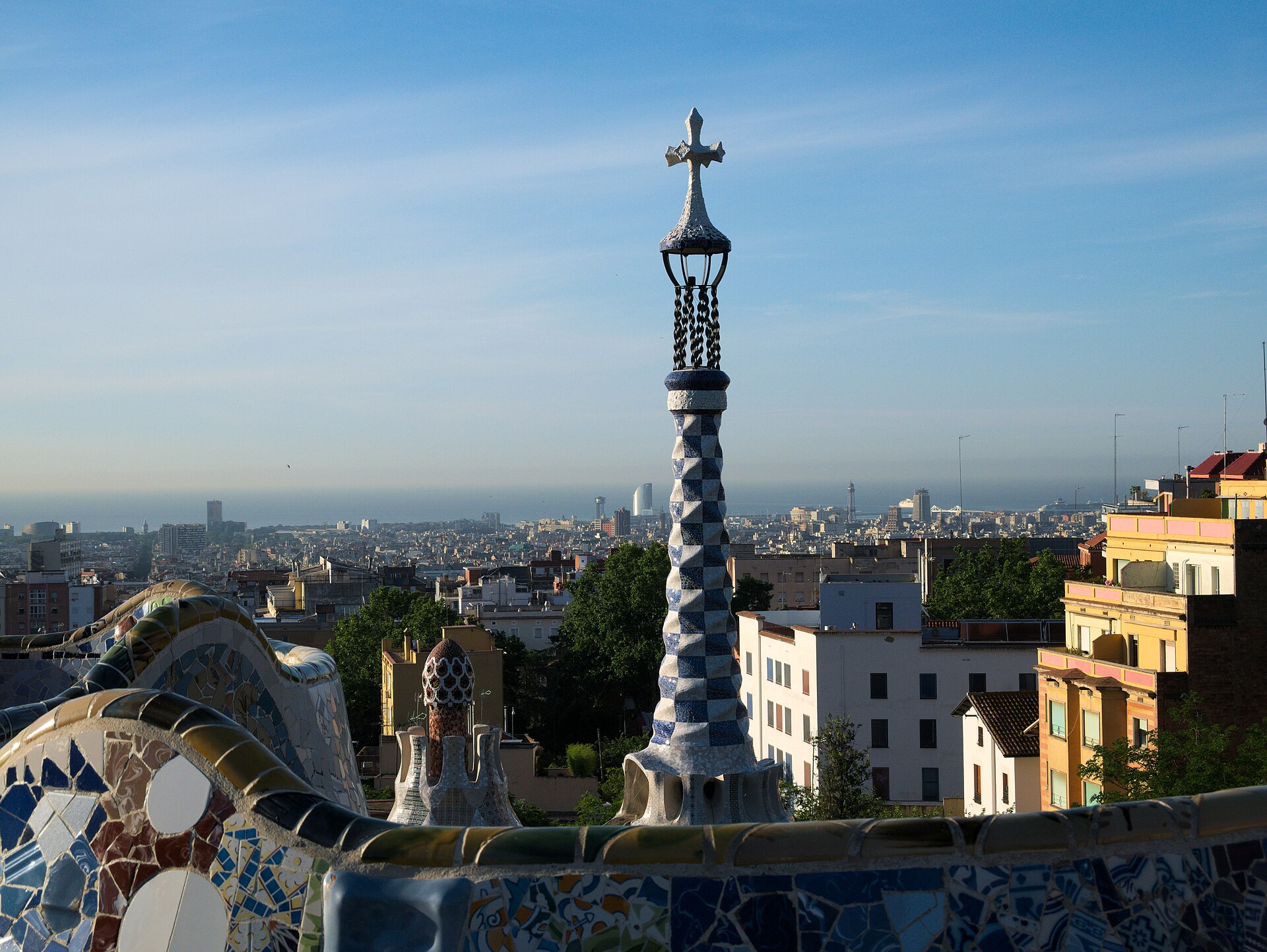 la panca a mosaico della piazza di park guell con la torre a scacchi del padiglione d’ingresso e barcellona fino al mare