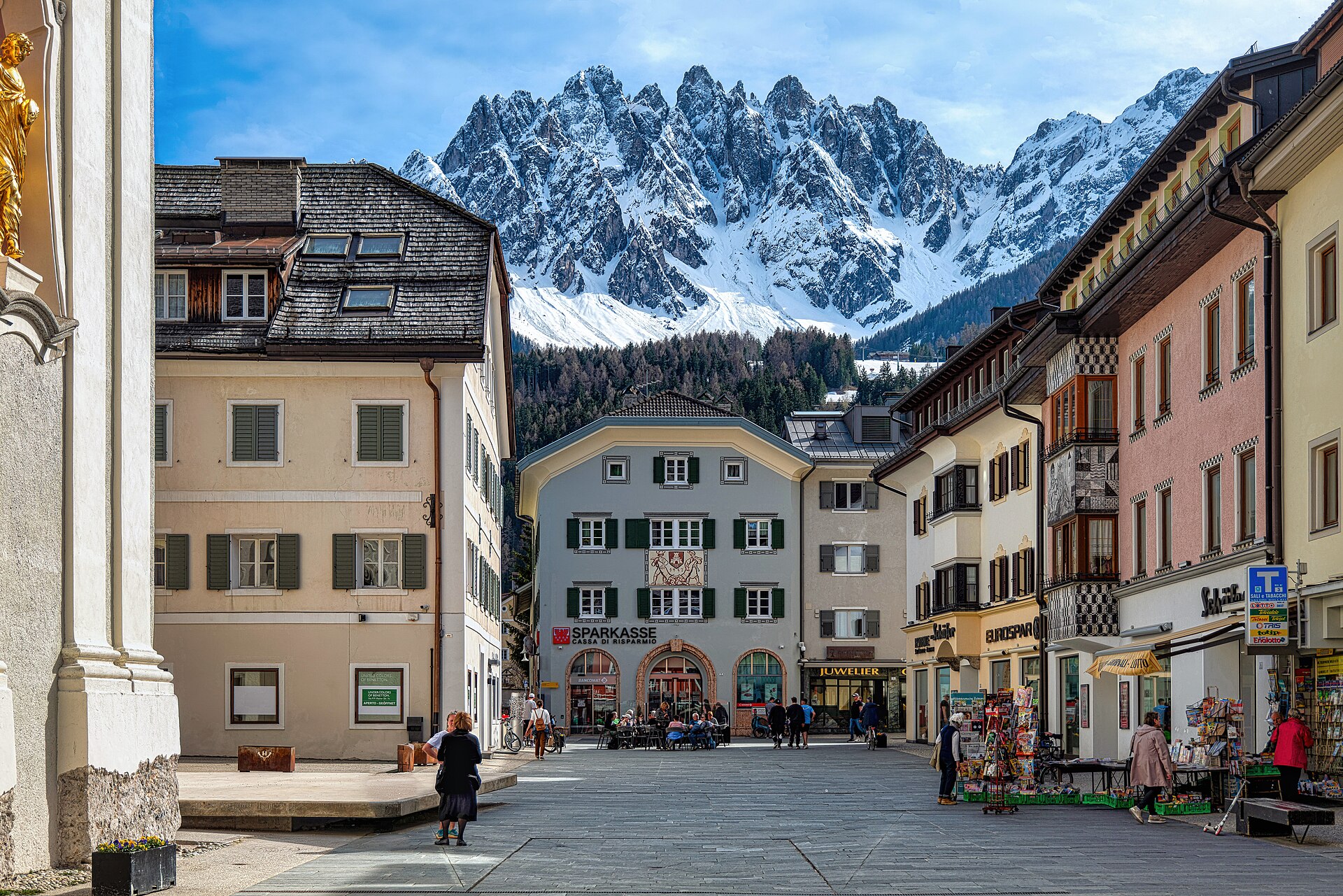 la plaza de san candido con sus casas pintadas y las cumbres nevadas de los baranci detras