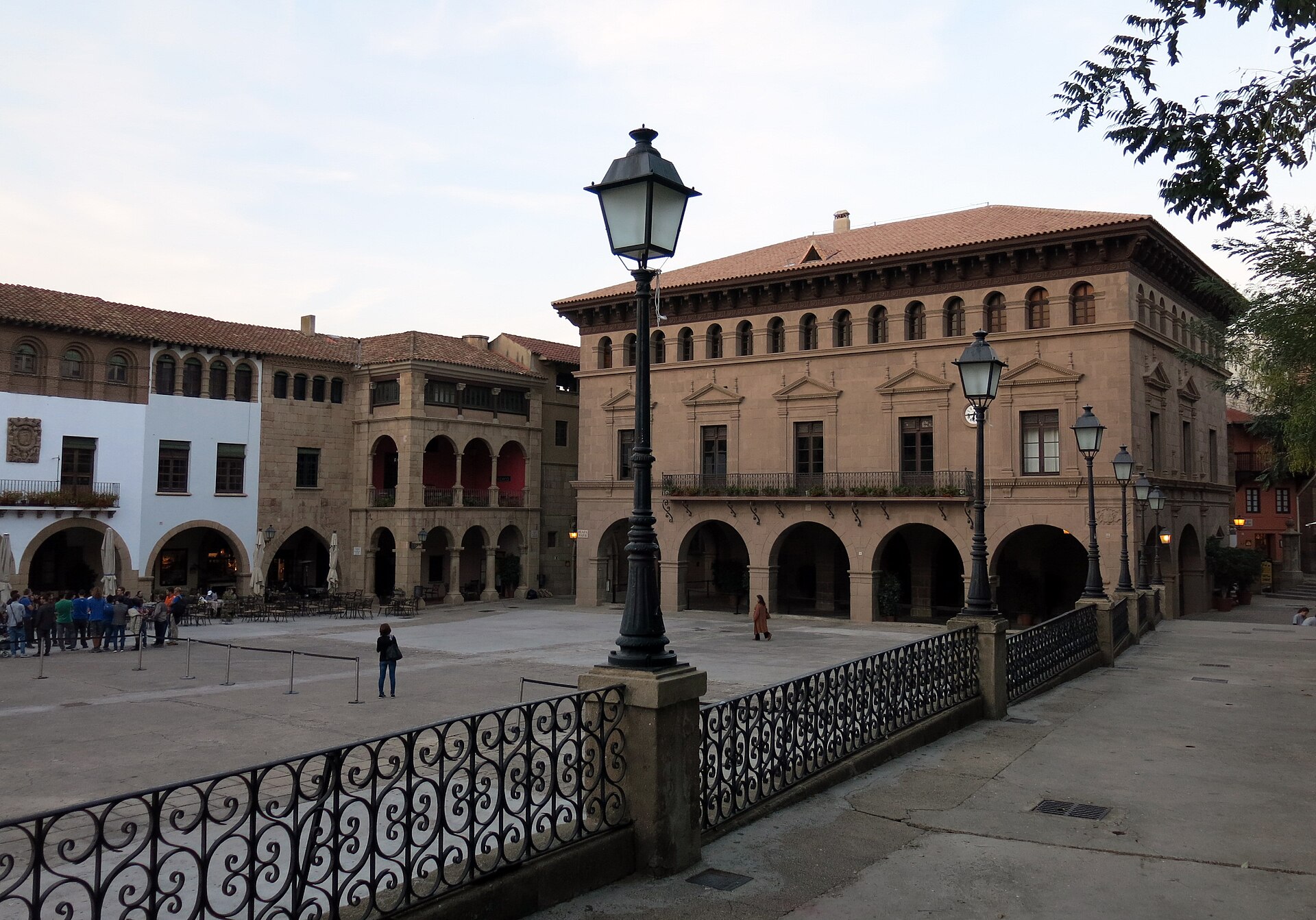 la plaza mayor del poble espanyol con il municipio di pietra di valderrobres, i portici e i lampioni, e una ringhiera di ferro in primo piano
