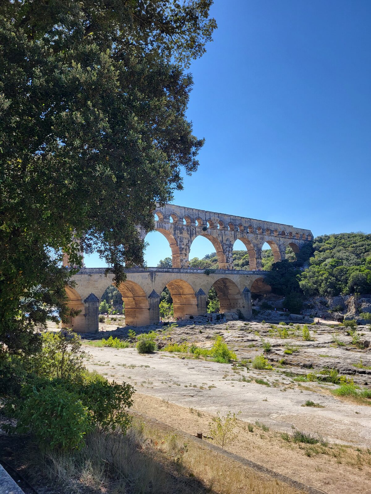 il Pont du Gard visto da valle, con i tre ordini di arcate e il letto asciutto del Gardon in primo piano