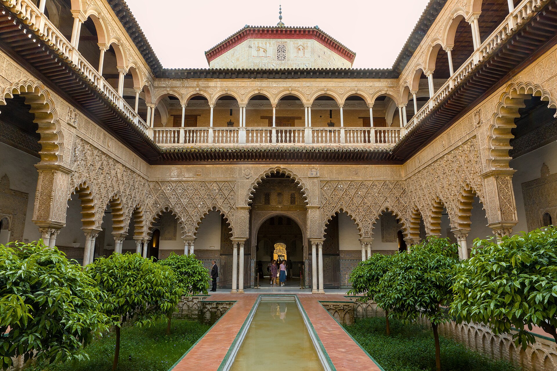 il patio de las doncellas del real alcazar di siviglia, con la vasca lunga fra due giardini ribassati, gli archi traforati e la loggia rinascimentale al piano di sopra