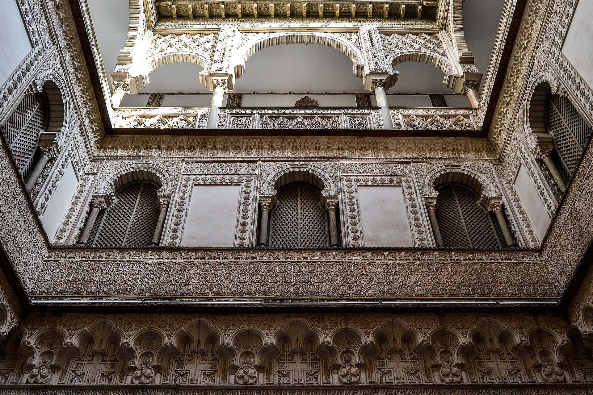 il patio de las munecas del real alcazar di siviglia visto dal basso, con le gallerie di archi decorati a stucco su tre piani