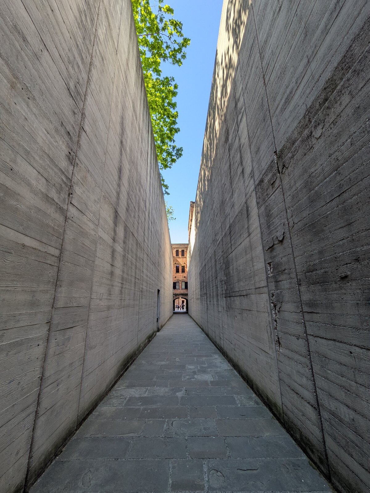 il corridoio d ingresso della risiera di san sabba stretto fra due alte pareti di cemento a vista