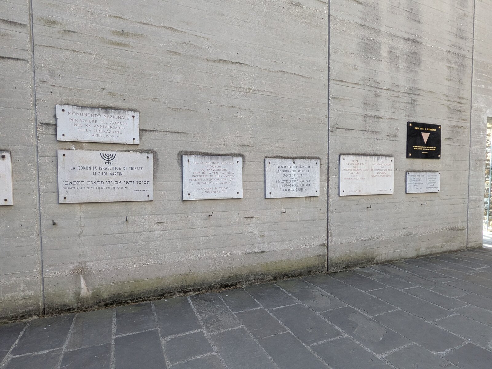 le lapidi commemorative allineate sul muro di cemento del percorso d ingresso della risiera di san sabba