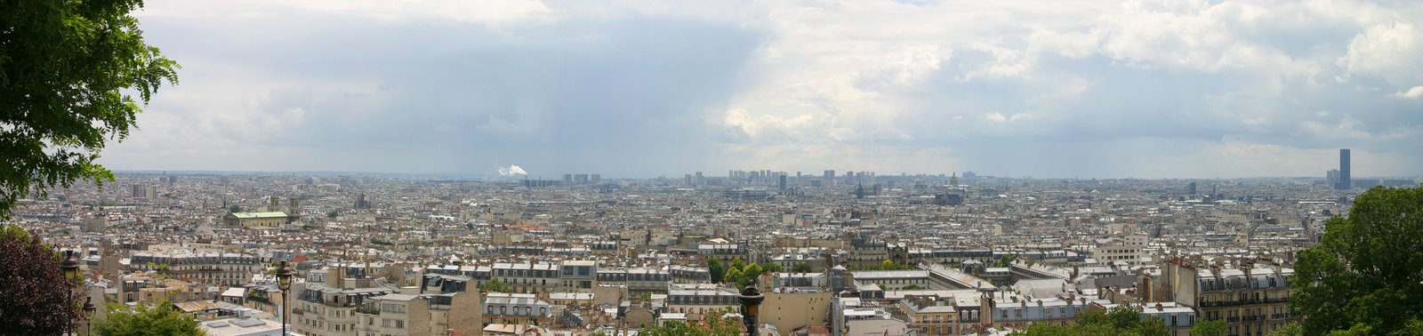 vista panoramica dei tetti di parigi dalla collina di montmartre, con gli edifici haussmanniani in primo piano e lo skyline della citta che sfuma all orizzonte sotto un cielo nuvoloso