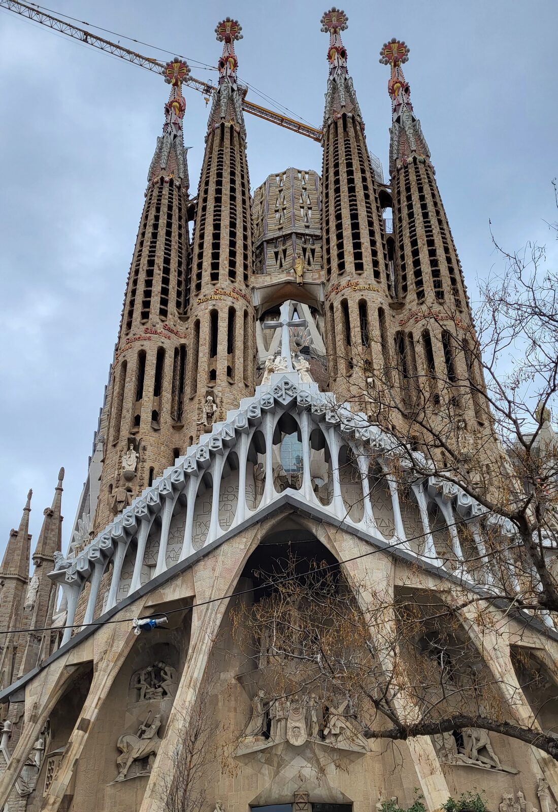 la façade de la Nativité de la Sagrada Família vue d’en bas, avec ses quatre tours et les grues