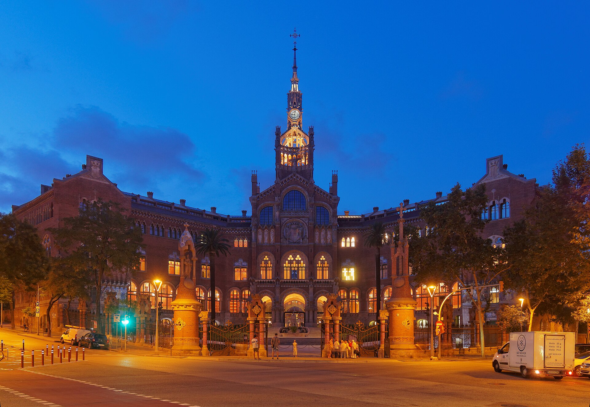 il padiglione dell’amministrazione di sant pau illuminato la sera, con la torre dell’orologio e il viale d’ingresso