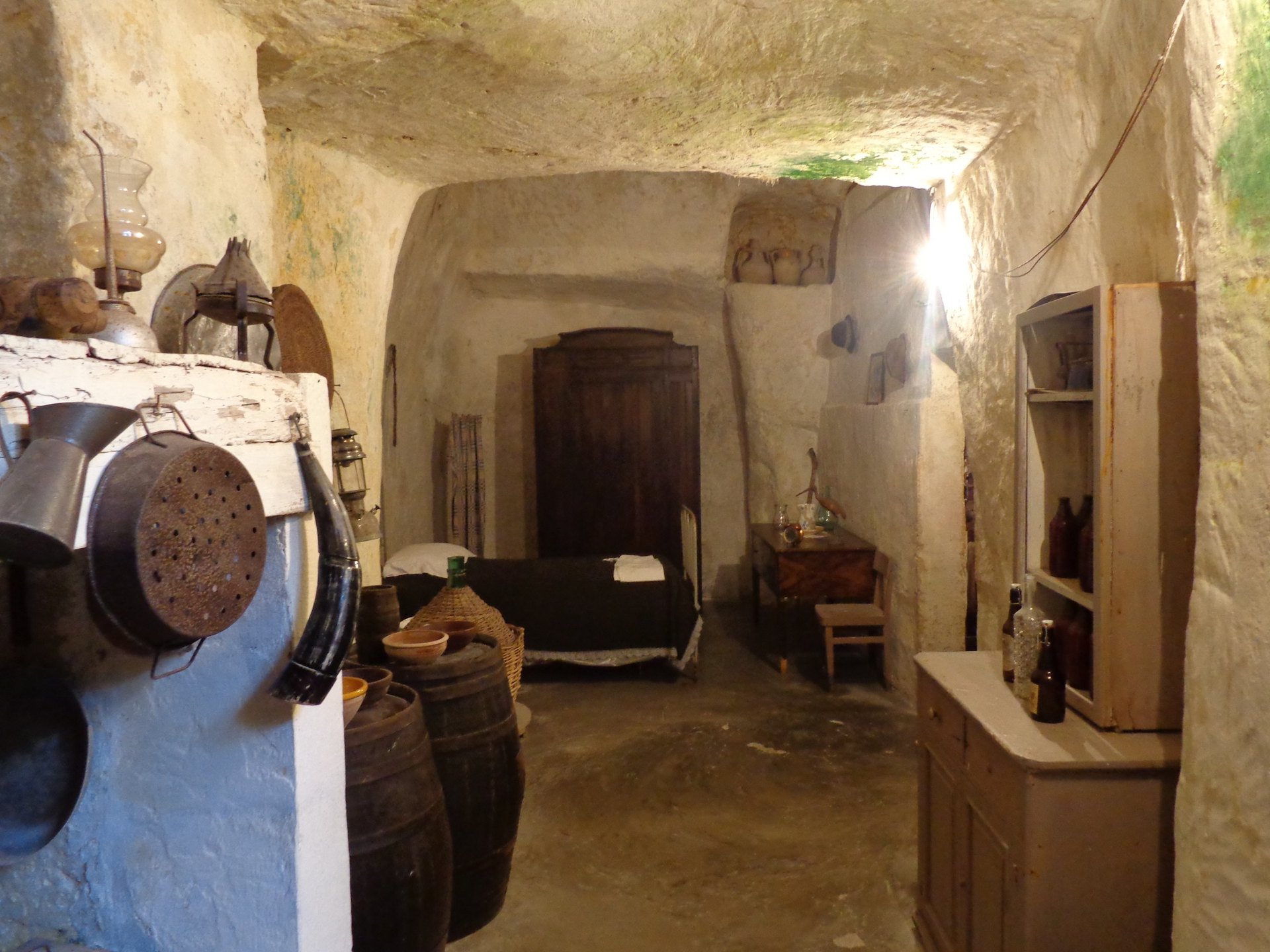 l interieur d une maison grotte a matera avec le lit l etable et les tonneaux contre la paroi de roche