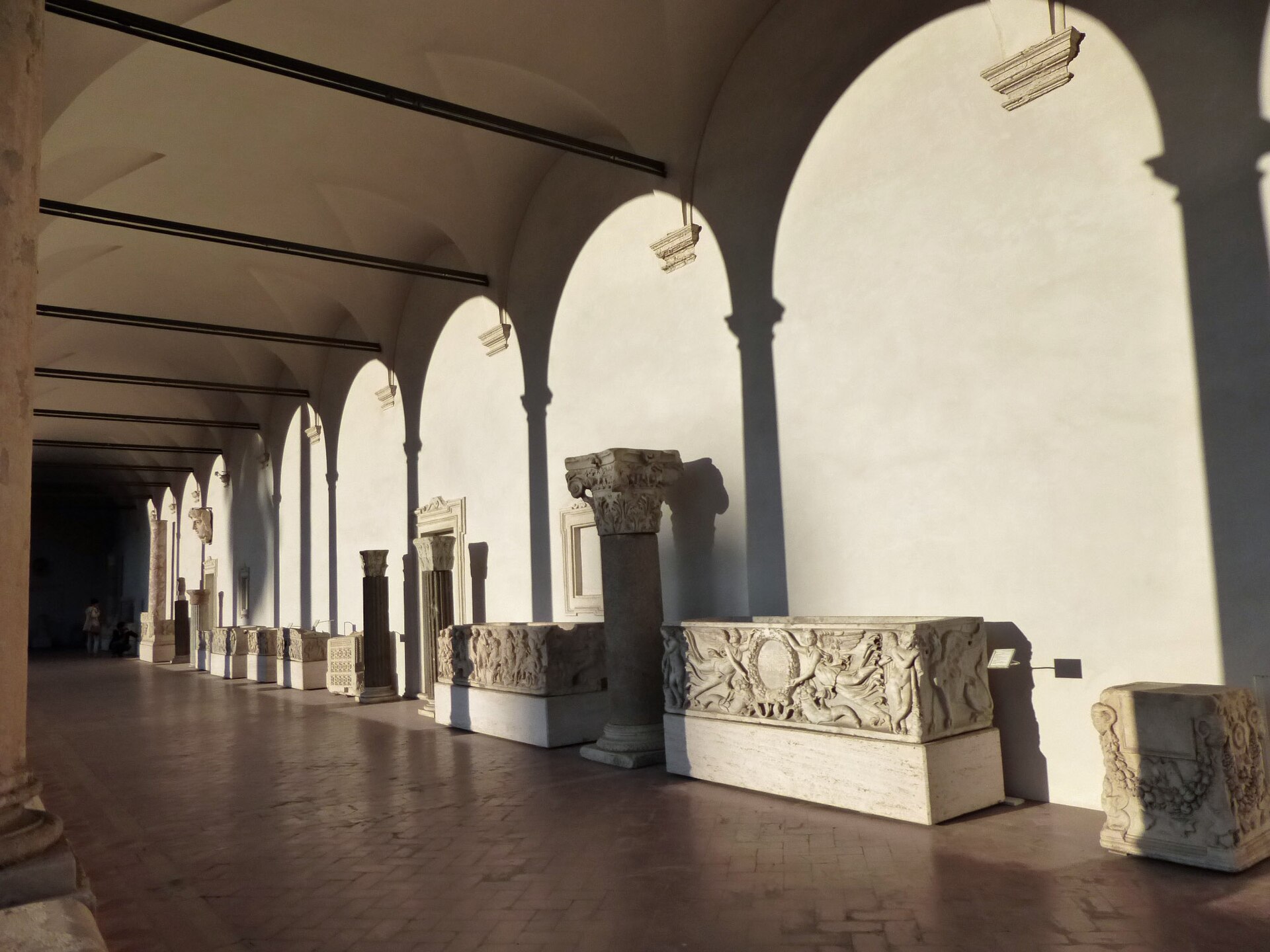 il portico del grande chiostro delle terme di diocleziano a roma, con i sarcofagi romani allineati lungo il muro sotto le arcate