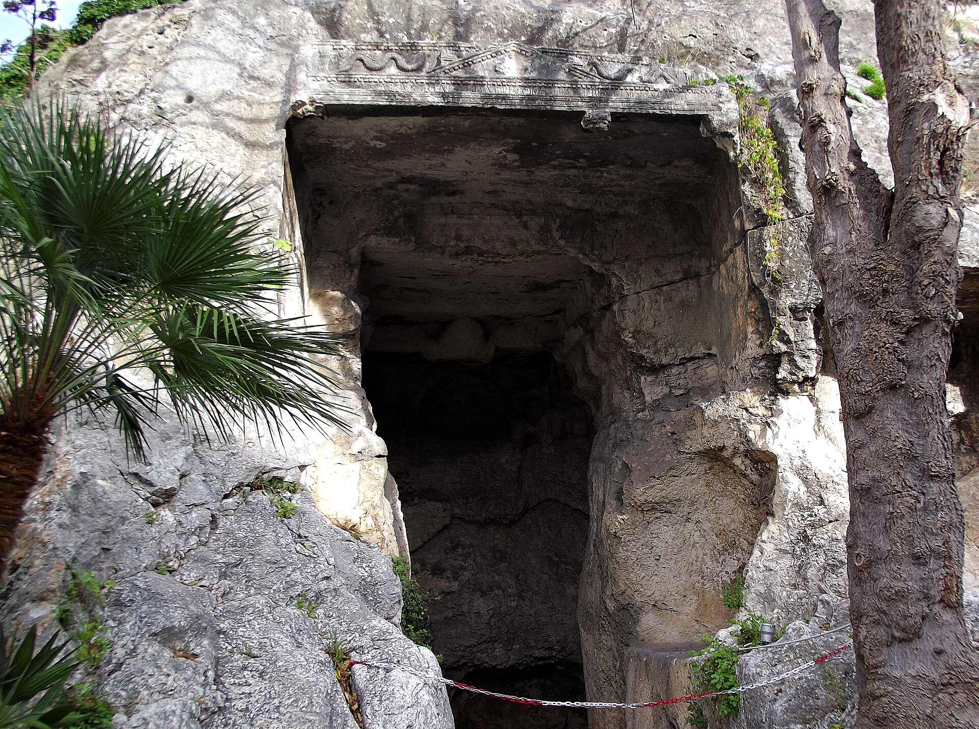 la facciata scavata nella roccia della grotta della vipera a cagliari con il timpano scolpito e la camera buia