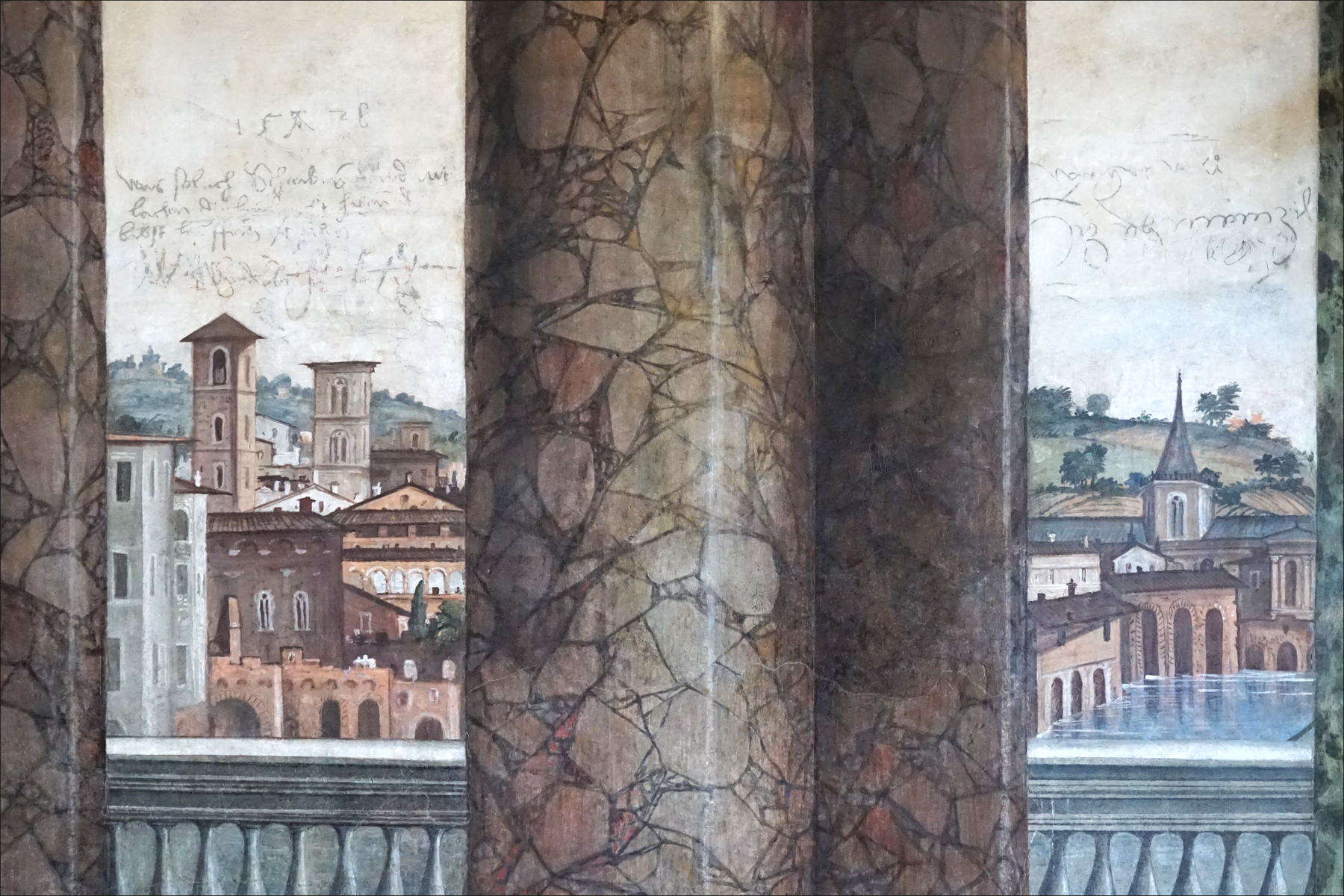 le colonne dipinte della sala delle prospettive con la veduta di una citta fra l una e l altra e, in alto a sinistra, un graffito dei lanzichenecchi con la data 1528