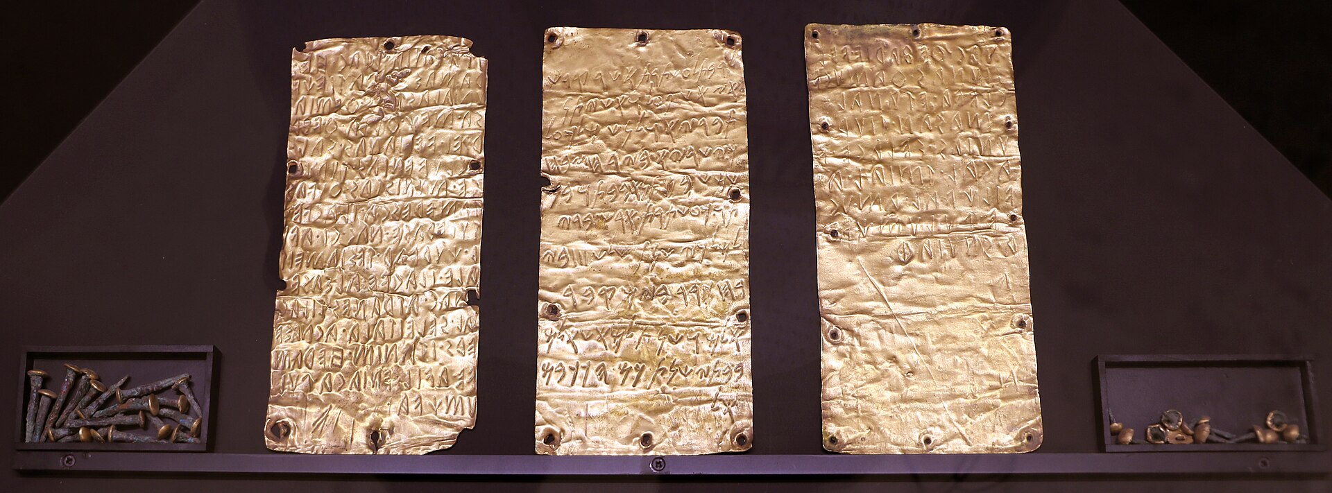 le tre lamine d oro di pyrgi nella vetrina di villa giulia, due scritte in etrusco e una in fenicio, con accanto i chiodi che le fissavano allo stipite